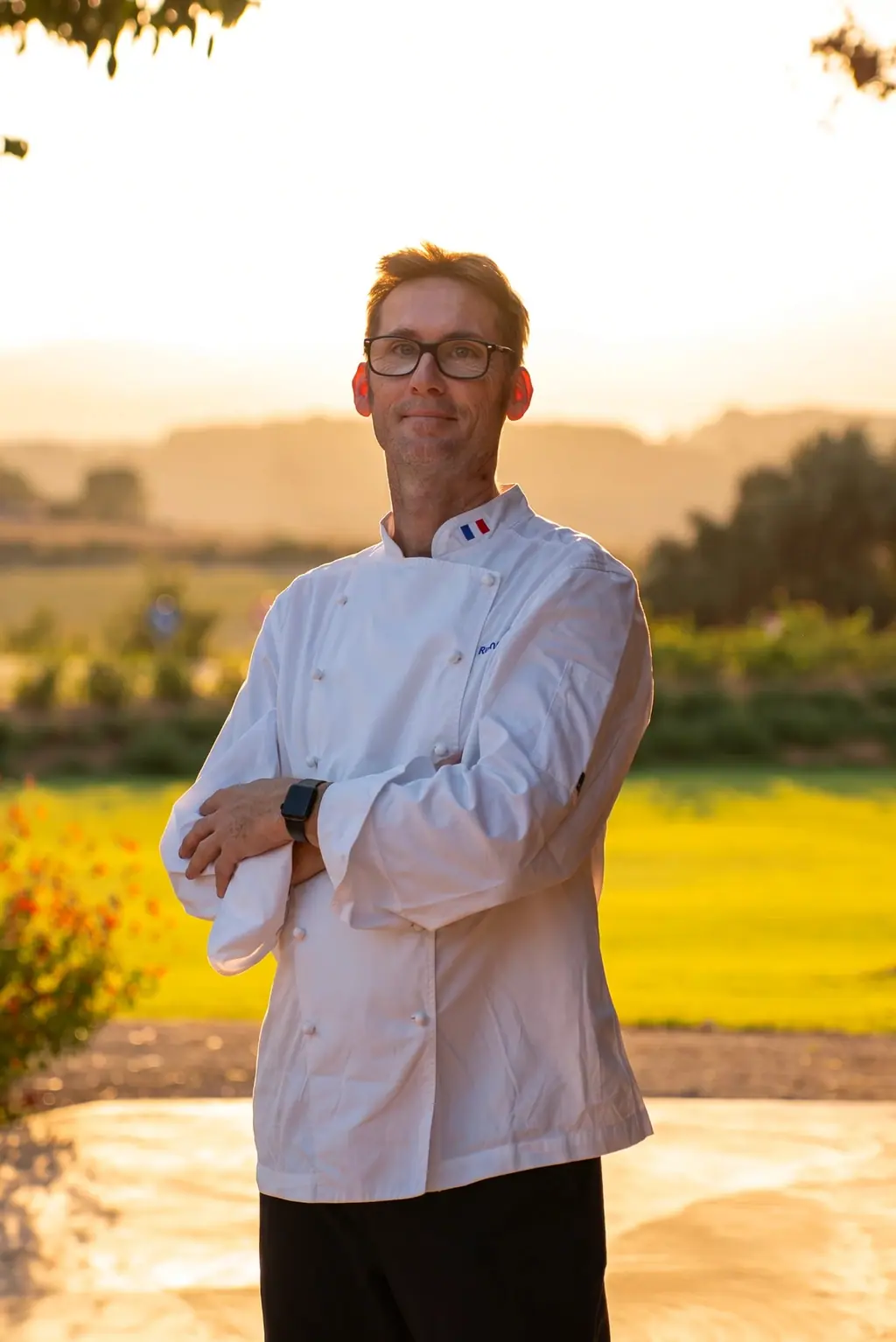 Chef Bruno Bonnier outdoors at golden hour, in his whites