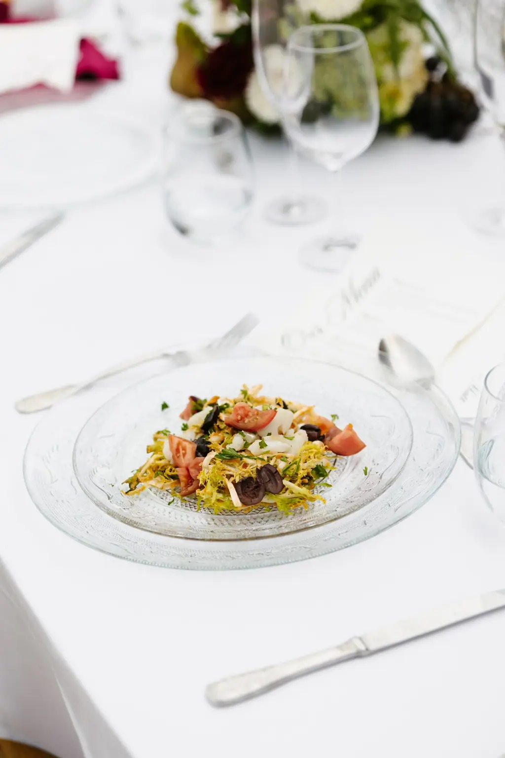 A plated salad of cod, tomato and black olives